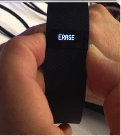 Fitbit-Tracker mit dem Text „ERASE“ auf dem Bildschirm